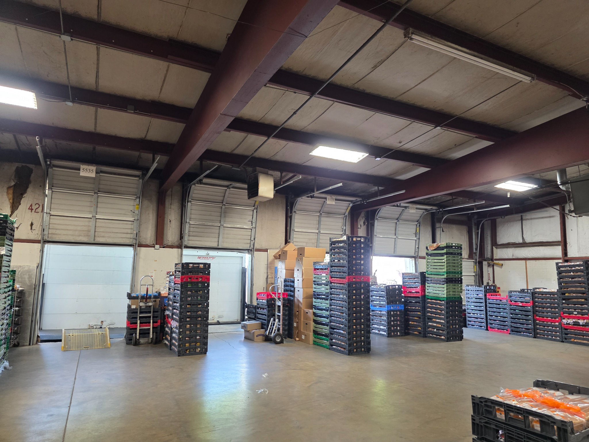 Gomez Distributor Inc warehouse in Greenville with loading doors, stacked bread trays, and handling equipment
